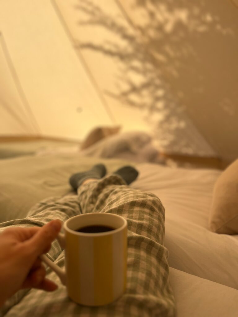 Inside a bell tent - cosy bedding and morning coffee
