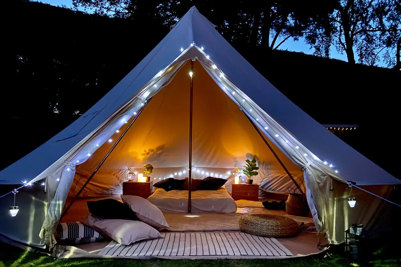 Bell tent glowing warm against the night sky