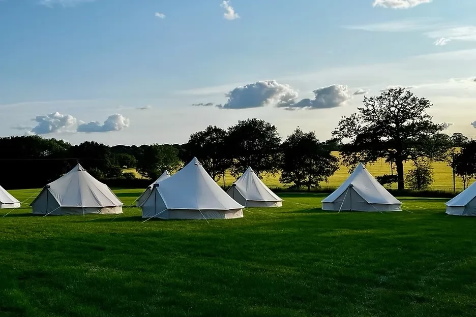 Bell tents pitched in a row on a festival campsite
